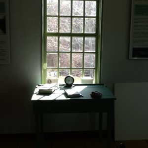green writing desk in front of sash window with sunlight streaming in