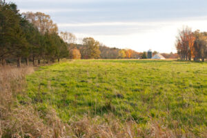 Field surrounded by trees changing for autumn. Roof of farm in the distance. View south in area of trail proposed by Minute Man National Historical Park, the Town of Concord, and The Thoreau Farm Trust. Photo: Nick Reinhardt